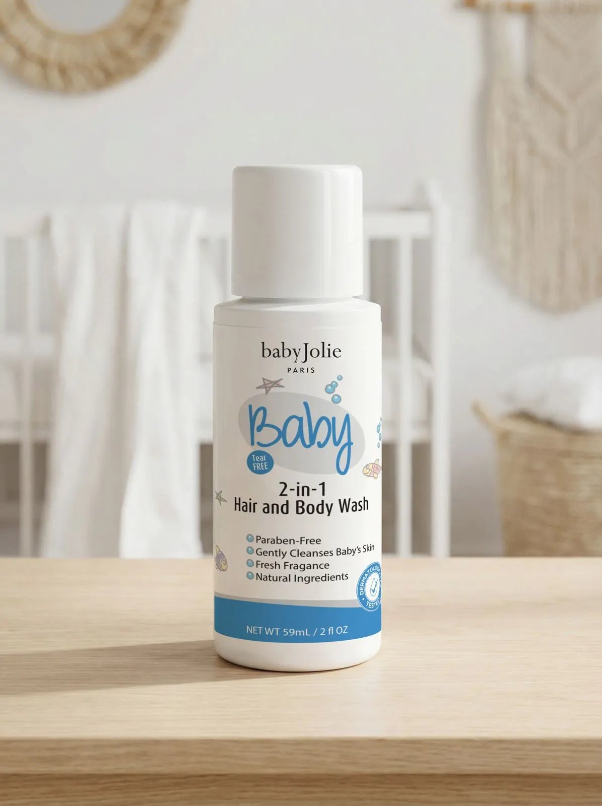 Baby Jolie 2oz travel-size 2-in-1 hair and body wash bottle with white cap and blue label on a wooden surface.