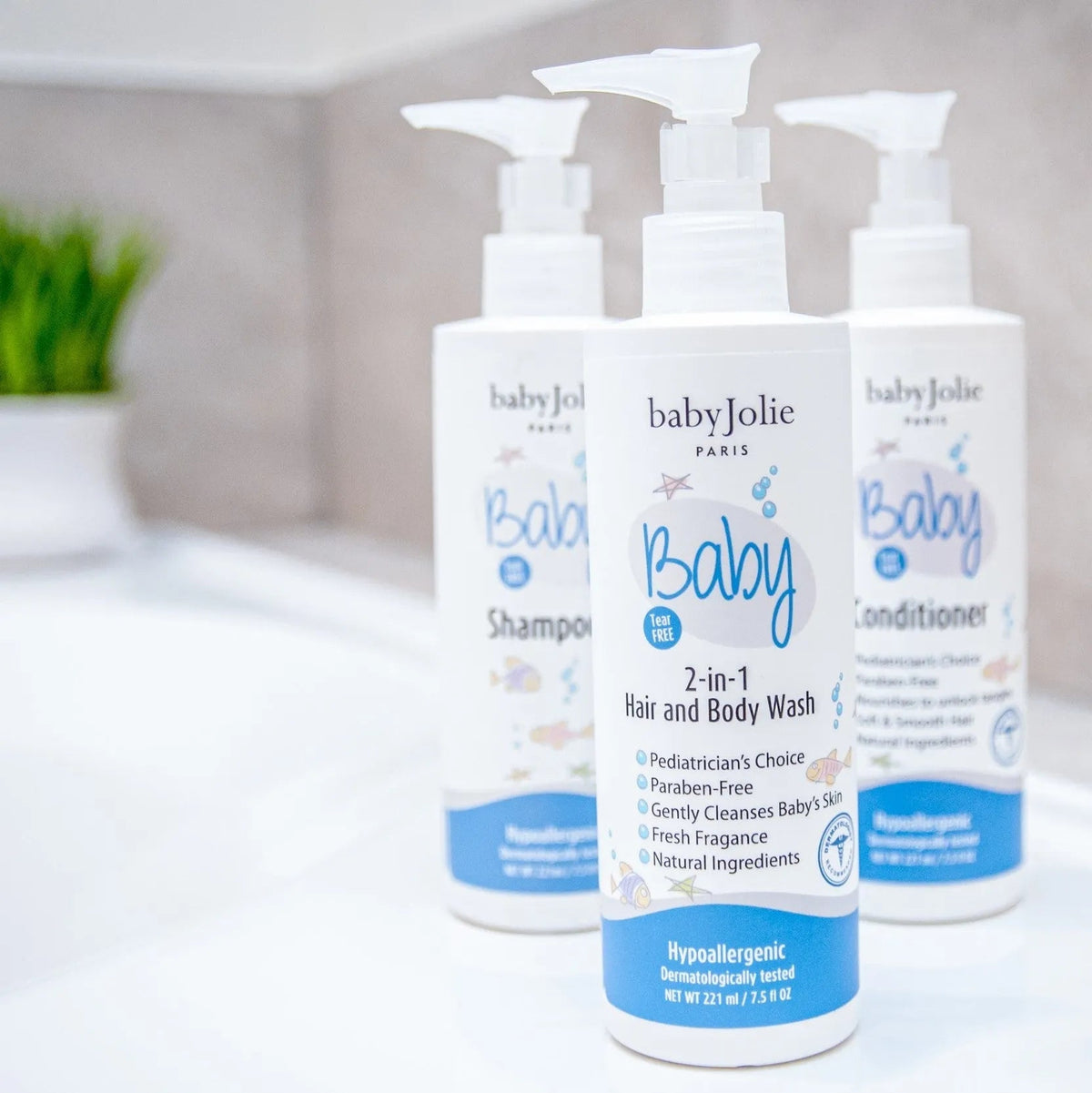 Three white Baby Jolie pump bottles for baby hair and body wash on a clean bathroom counter.