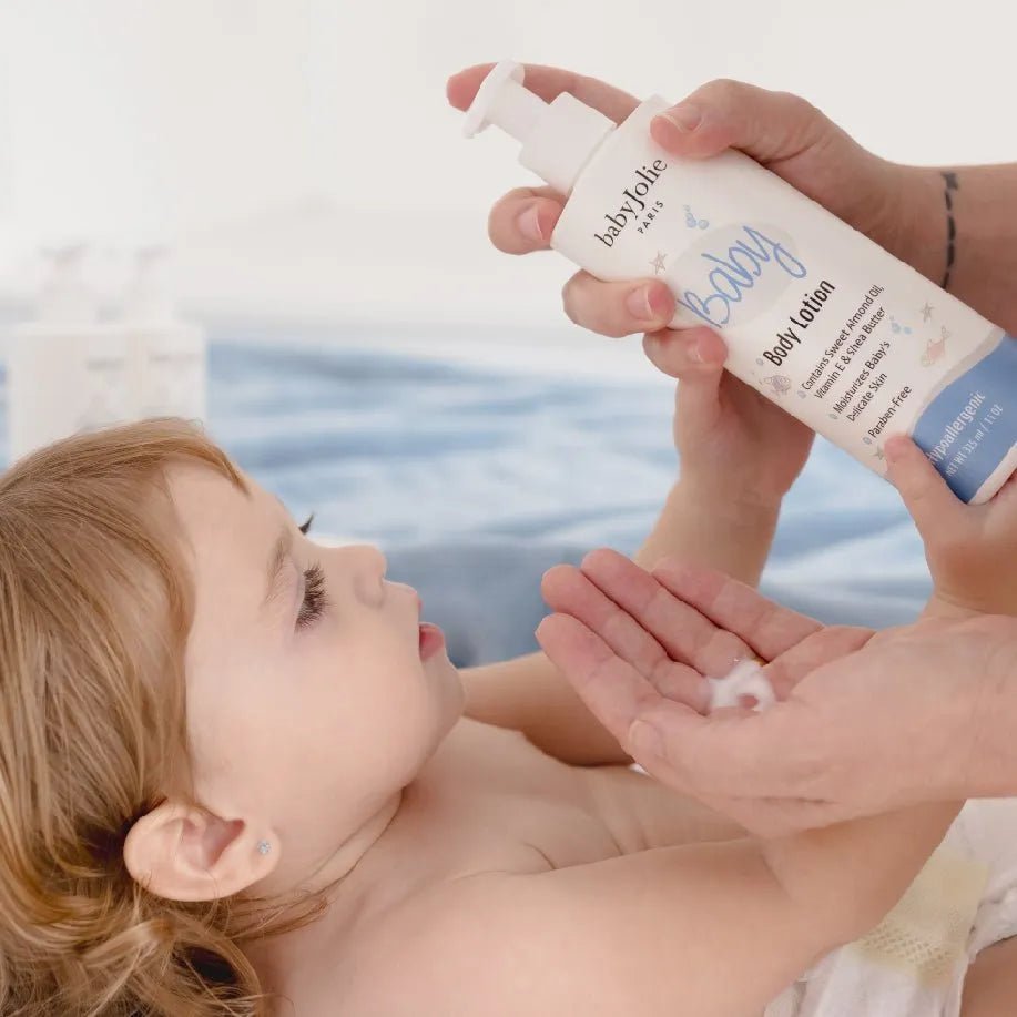 Parent applying Baby Jolie moisturizing body lotion from a white pump bottle onto a baby's hand.
