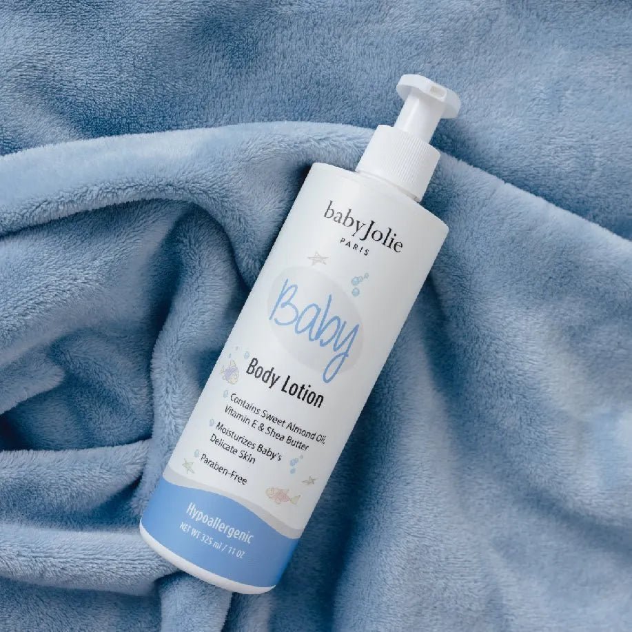 Baby Jolie 11oz body lotion bottle with a white pump, resting on a soft, textured blue plush fabric background.