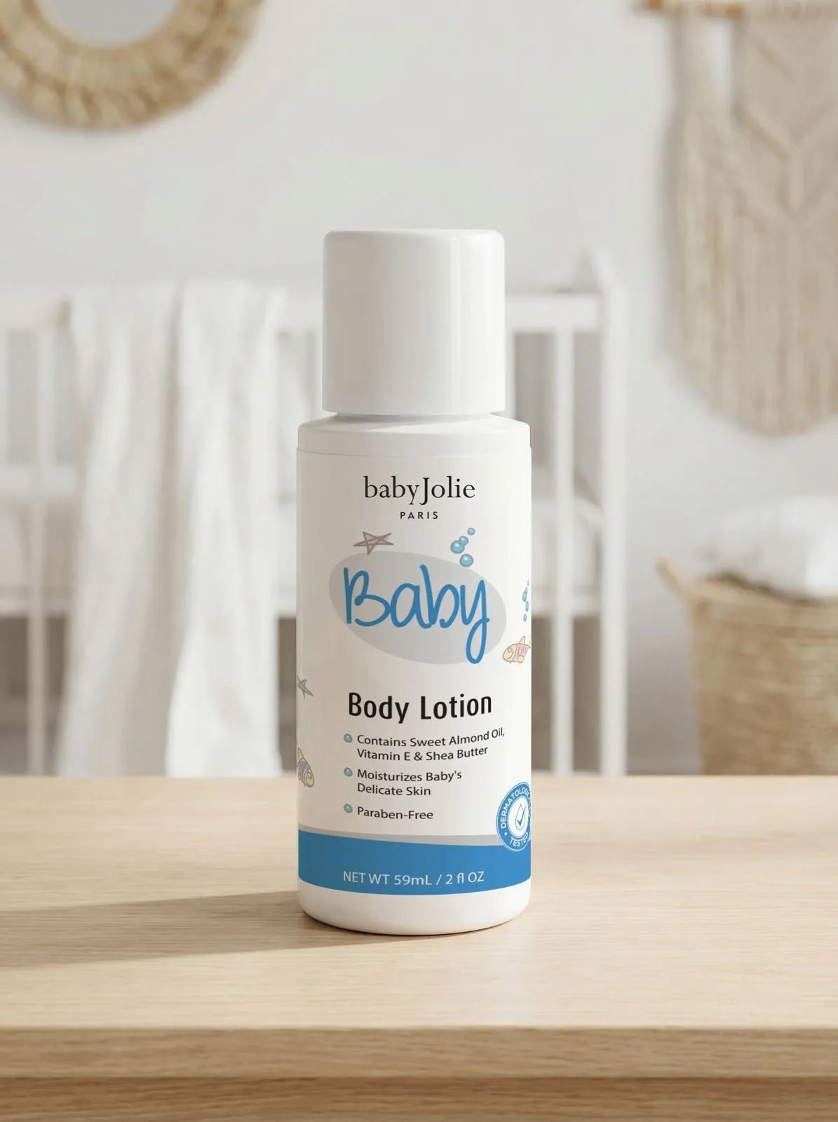 White 2oz travel-size Baby Jolie body lotion bottle with blue accents, sitting on a wooden surface in a nursery.