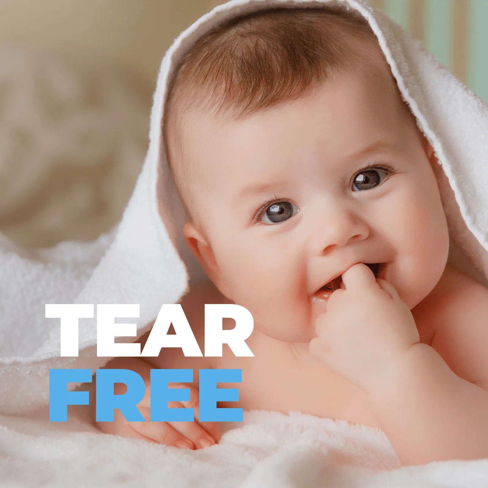 Smiling baby wrapped in a soft white towel with the text Tear Free overlaid in white and blue.