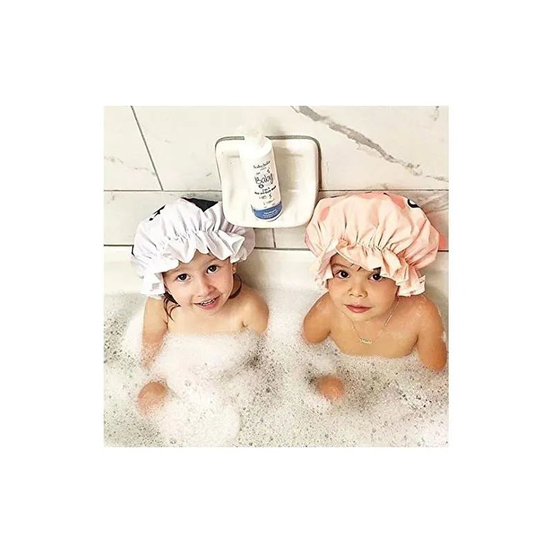 Two children wearing shower caps in a bubble bath with a bottle of Baby Jolie 2-in-1 Hair and Body Wash on the ledge.