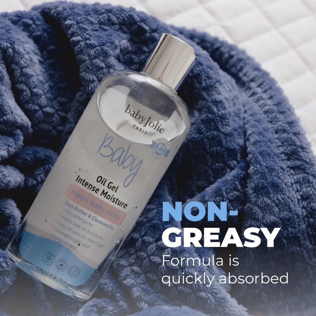 Clear bottle of babyJolie intensive moisture oil gel with a silver cap, resting on a soft, textured navy blue blanket.