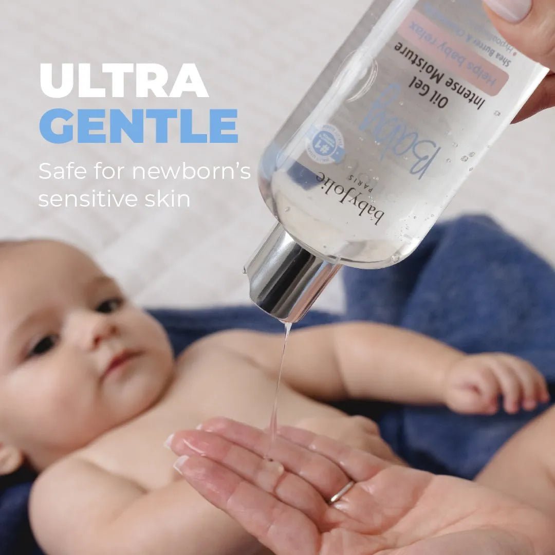 Clear Baby Oil Gel being poured from a transparent bottle onto a hand above a baby, with Ultra Gentle text overlay.