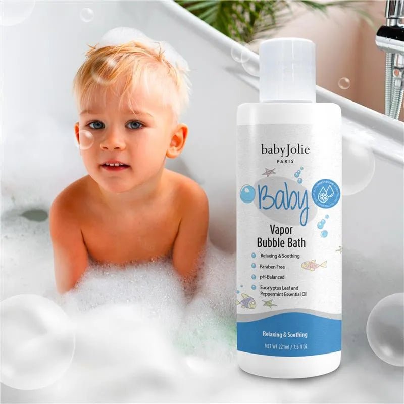 Baby Jolie 7.5 oz vapor bubble bath bottle with blue label next to a toddler playing in a bubbly bathtub.
